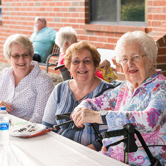 seniors smiling and talking outside of assisted living center