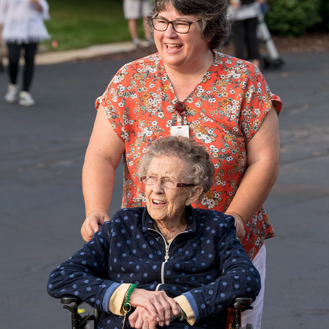 staff proving specialized senior care to elderly woman in wheelchair